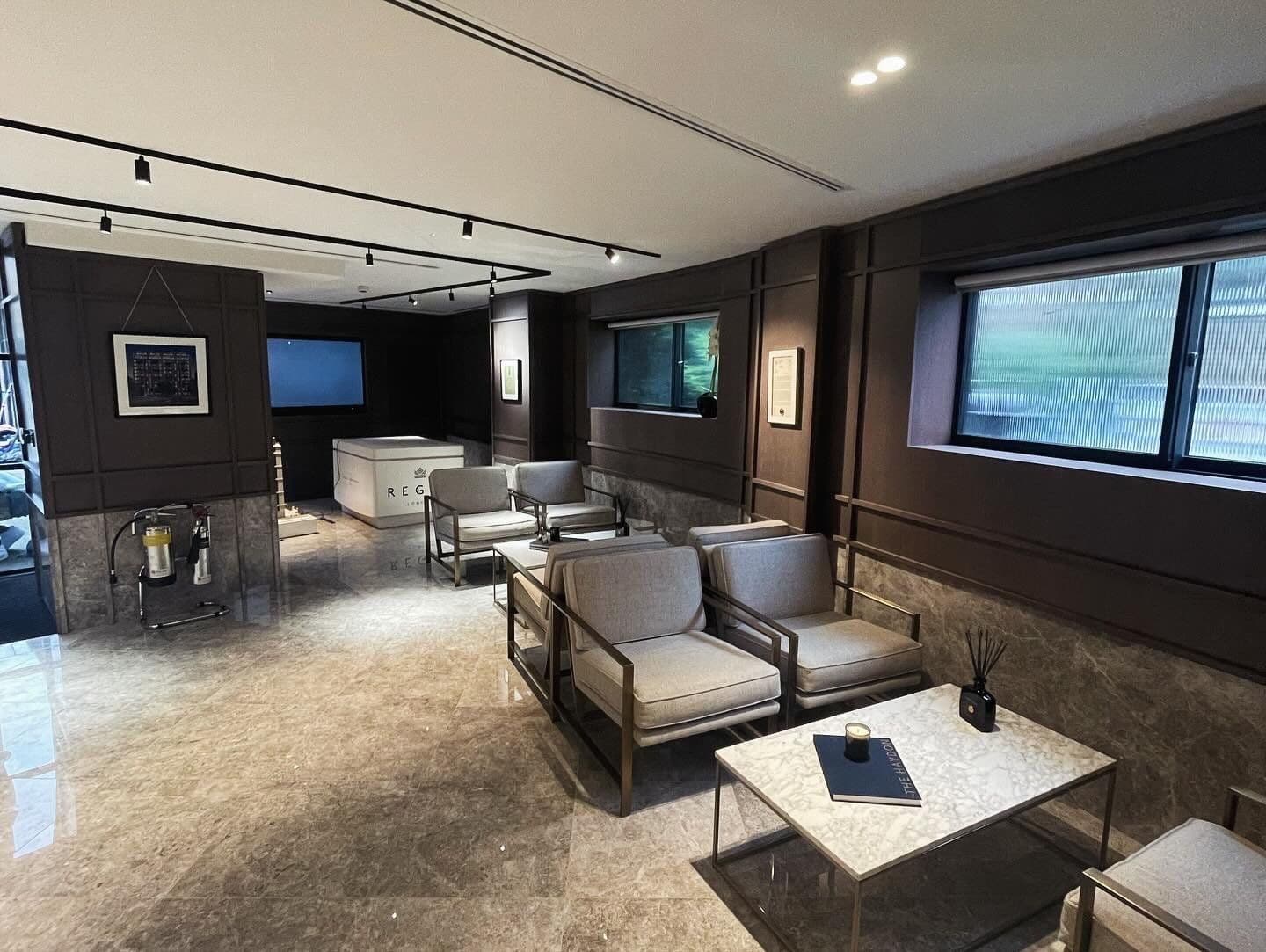 Commercial breakout lounge with dark wall panelling, marble floor and lounge seating