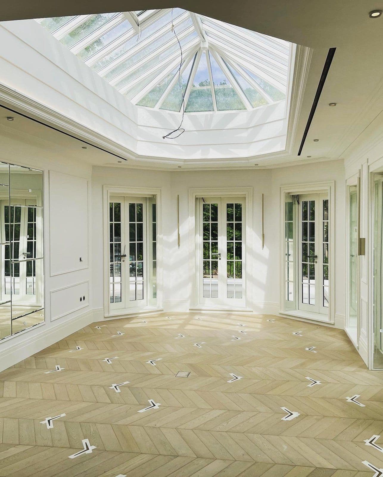 Panelled room with chevron parquet flooring beneath a roof lantern