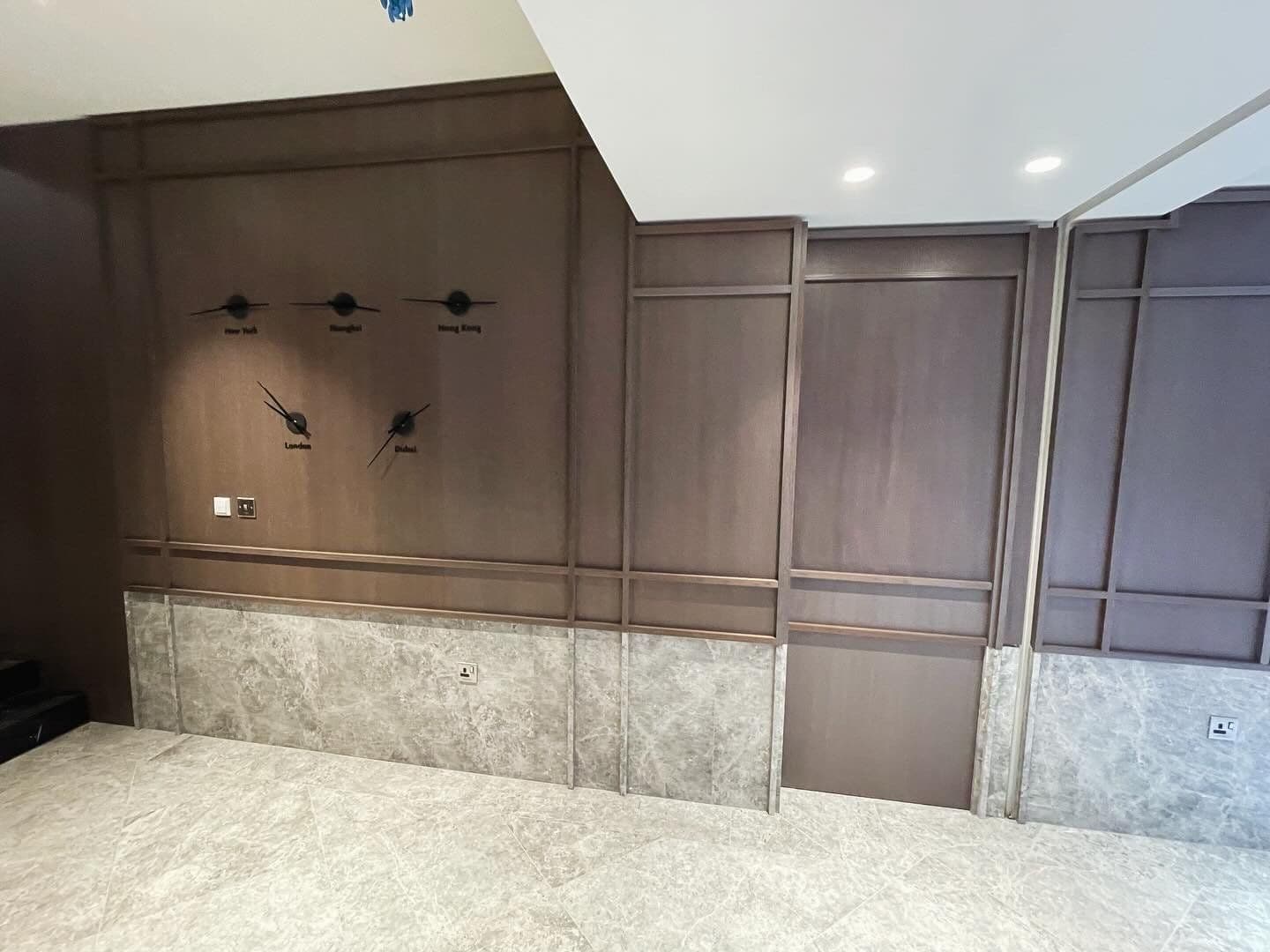 Dark timber wall panelling over a marble-clad dado in a commercial space