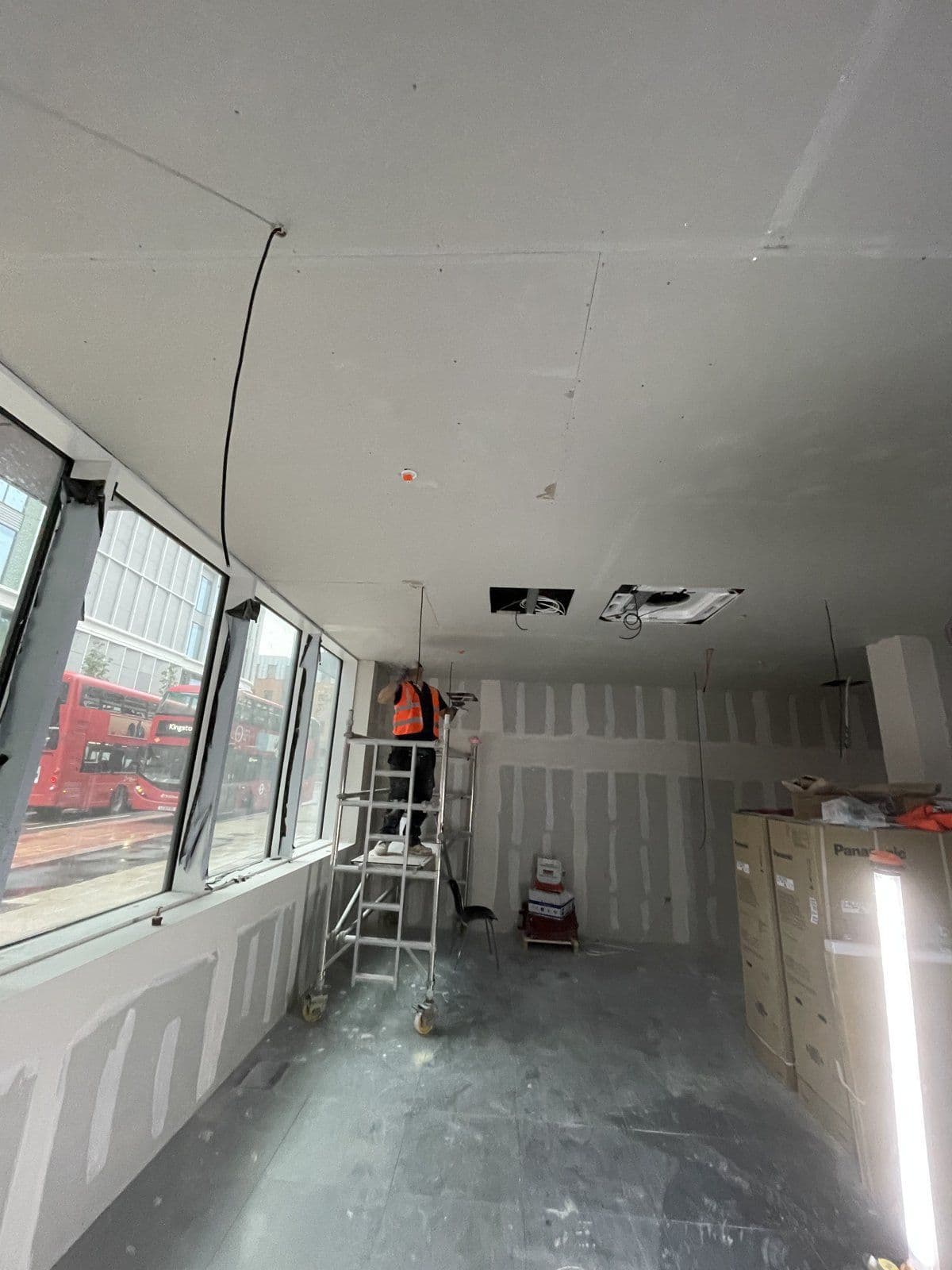 Plasterboard linings installed around full-height windows on a commercial floorplate