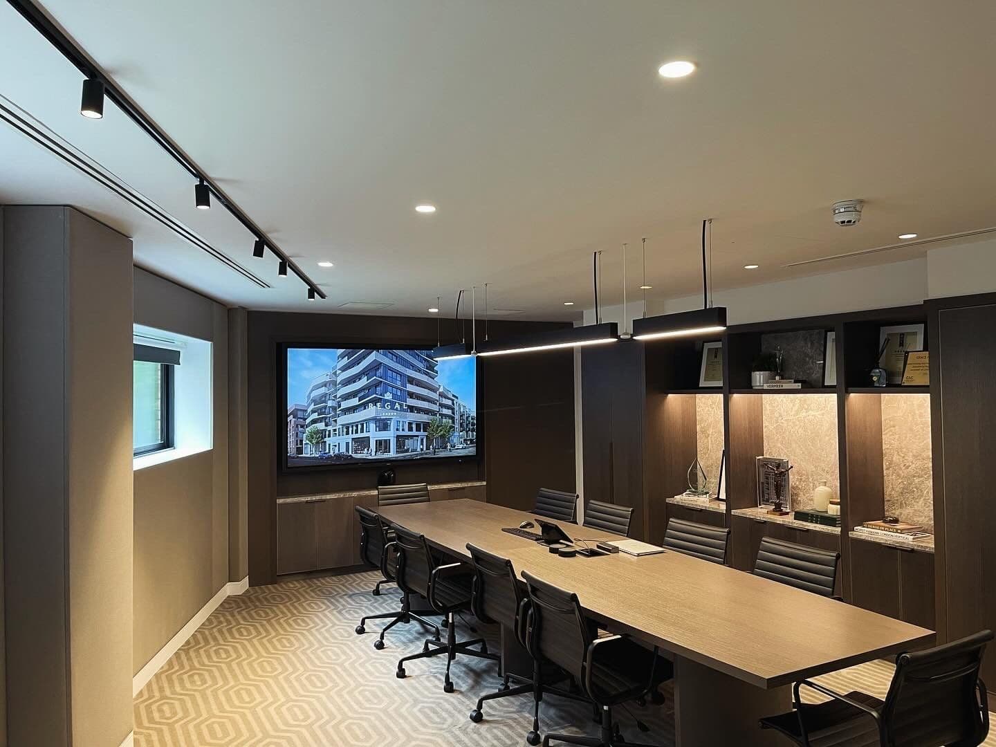 Executive boardroom fit-out with dark timber panelling, long meeting table and presentation wall