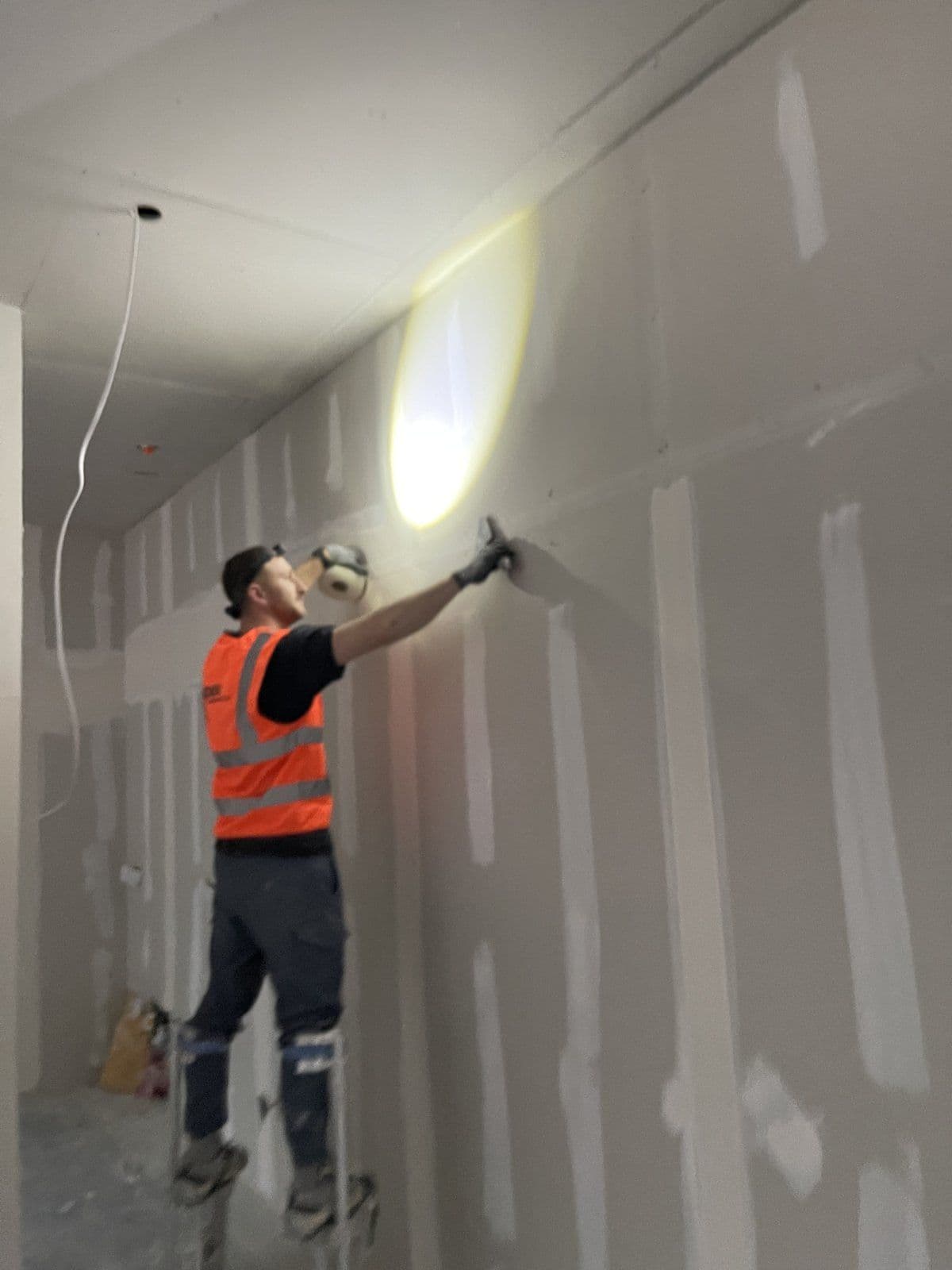Operative sanding taped plasterboard joints on a commercial partition wall