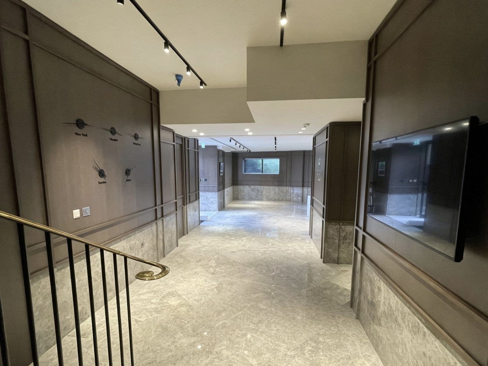 Commercial suite mid fit-out with full-height timber panelling, brass handrail and media walls
