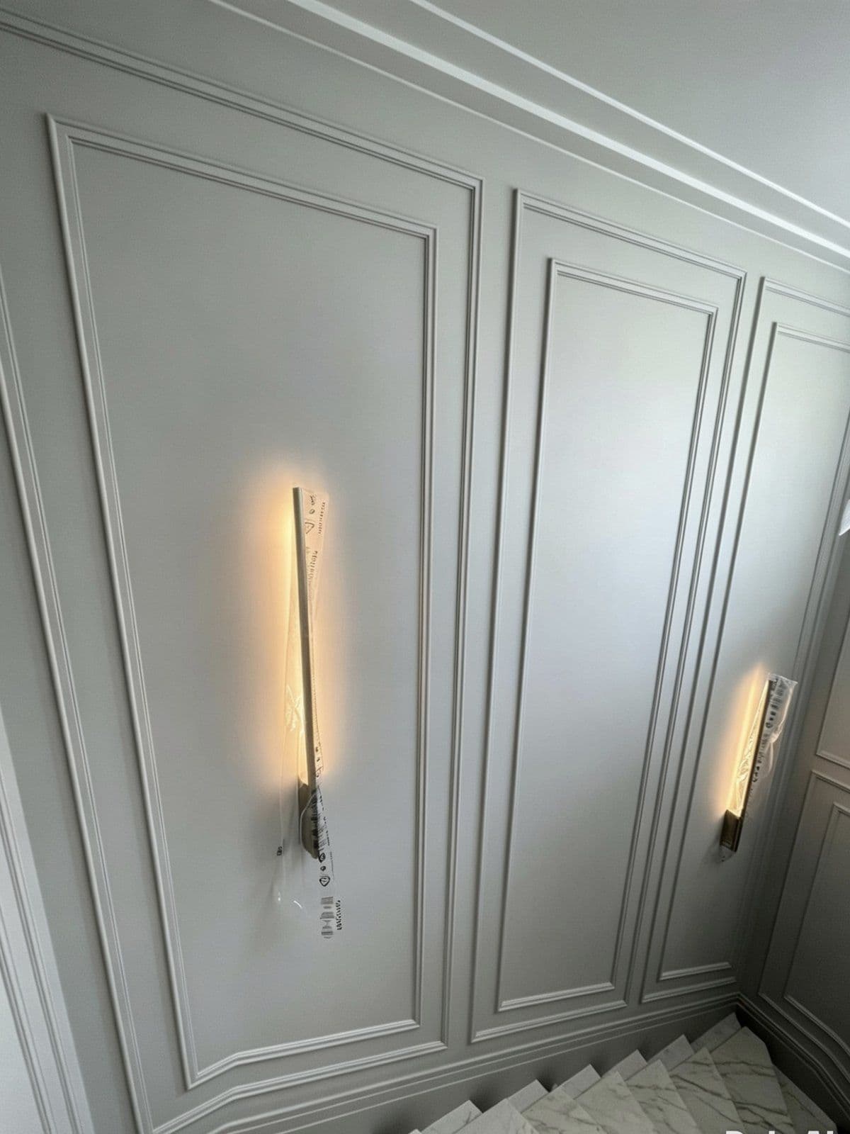 Decorated panelled staircase wall with feature wall lights