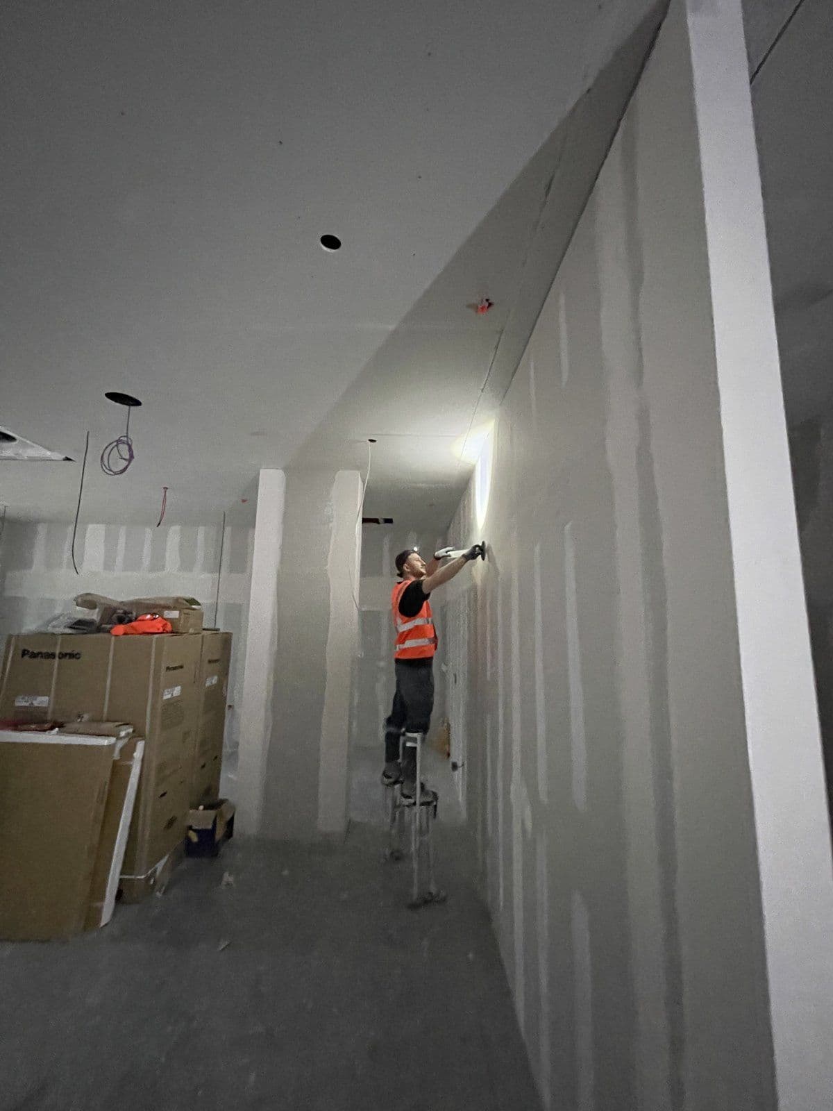 Operative on stilts taping full-height plasterboard partitions