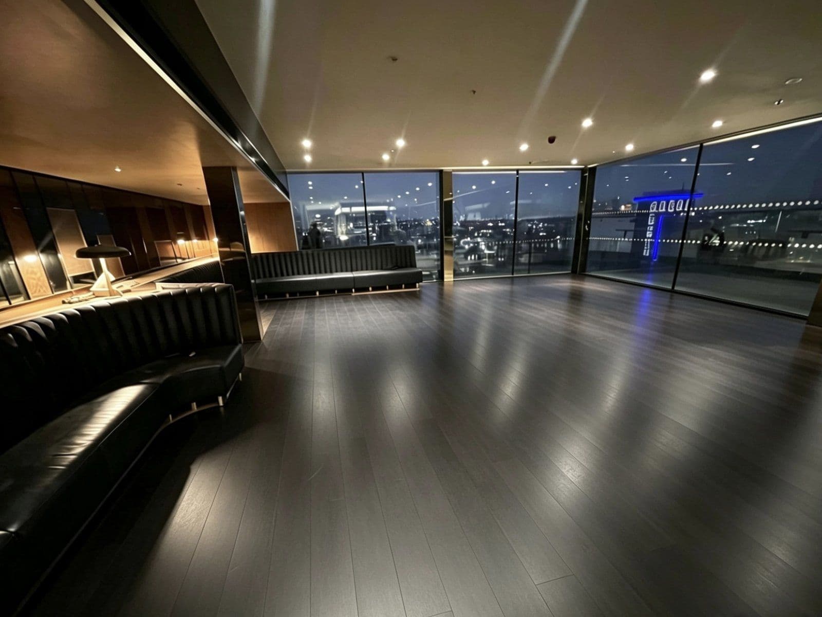 Bar and lounge fit-out with banquette seating, dark timber floor and floor-to-ceiling windows over the city