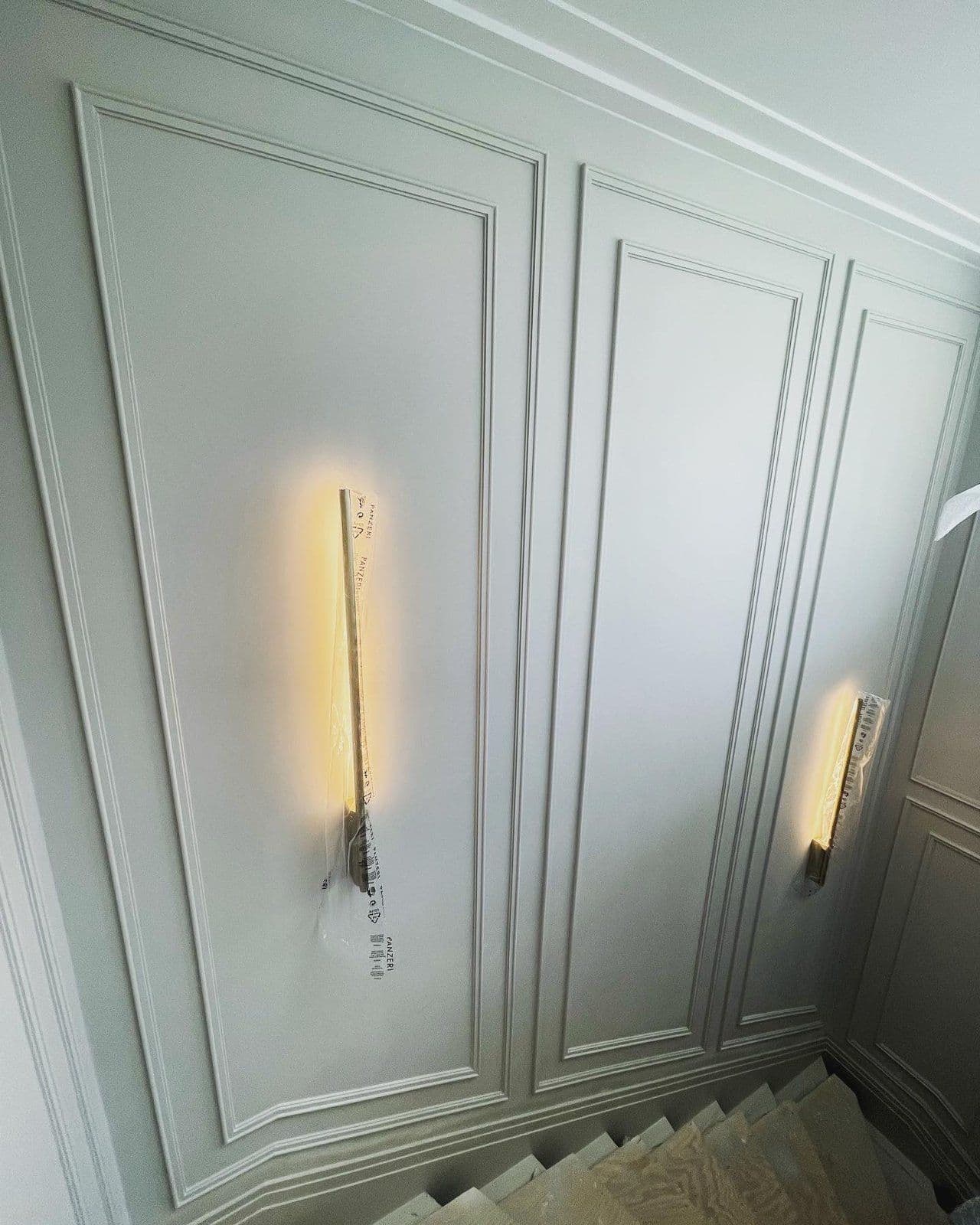 Sage-painted wall panelling detail with a feature wall light